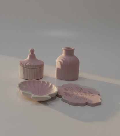 A collection of pastel pink ceramic home decor items, including a vase, a sell shaped tray, and a flower-shaped plate, arranged on a glossy white marble table in a modern, sunlit loft apartment with a city skyline view.